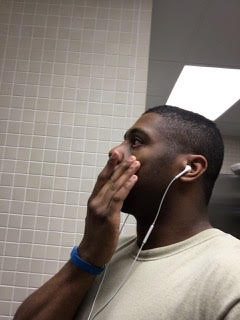 Lia's husband with his hand over his mouth, headphones in his ears, listening to an audiobook and reacting with shock.