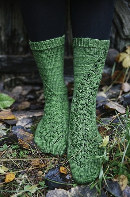 A close up of a pair of green socks with a climbing lace pattern