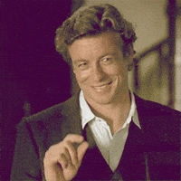 Simon Baker from the Mentalist grins and holds two fingers up to indicate something small