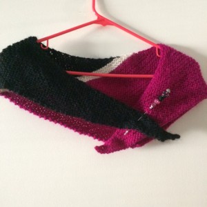 magenta and black shawl over a hangar with a pin holding it shut