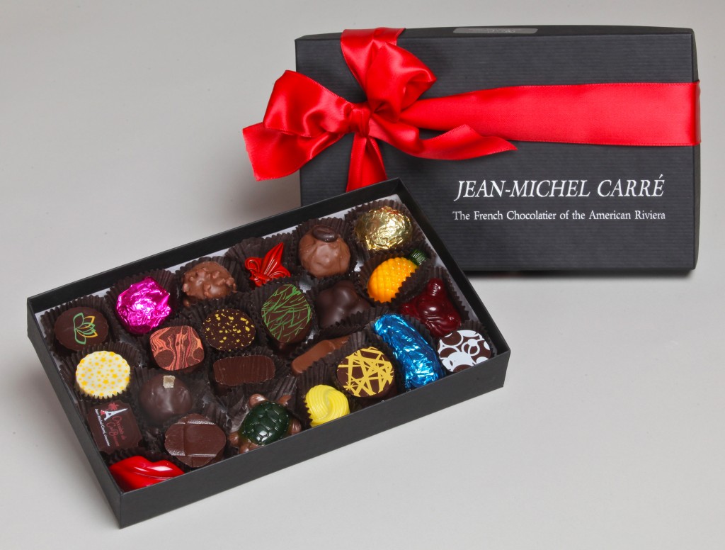 A box of 24 chocolates in multiple colors in a dark box with a red bow