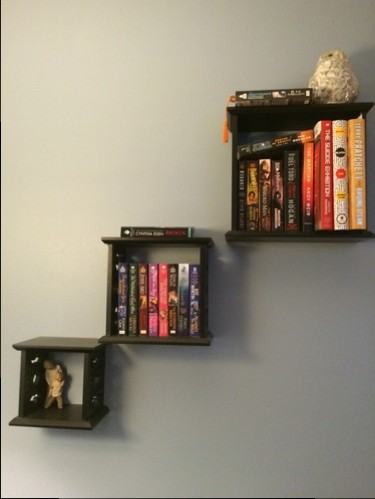 Three floating black square bookshelves, neatly stuffed with...more books.