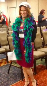 Tessa is a slender blonde woman and is wearing a burgundy dress with a blue and green feather boa and a silver hat that lights up. It's beyond awesome.