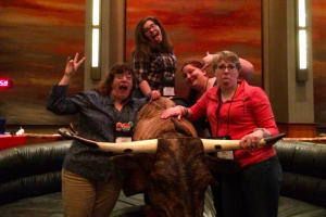 Carrie, RedHeadedGirl and Elyse around a mechanical bull with Amanda on top, all making silly faces