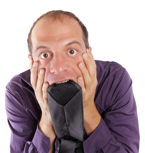Frustrated business man biting his grey necktie isolated on white