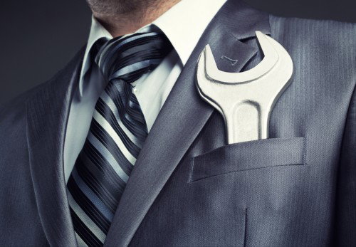 Businessman with an ENORMOUS spanner wrench in grey suit pocket