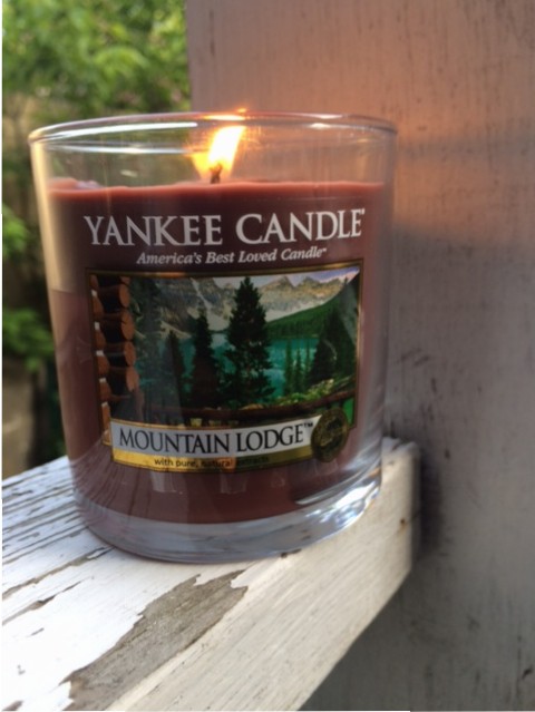 One small tumbler Mountain Lodge candle, cheerfully burning.