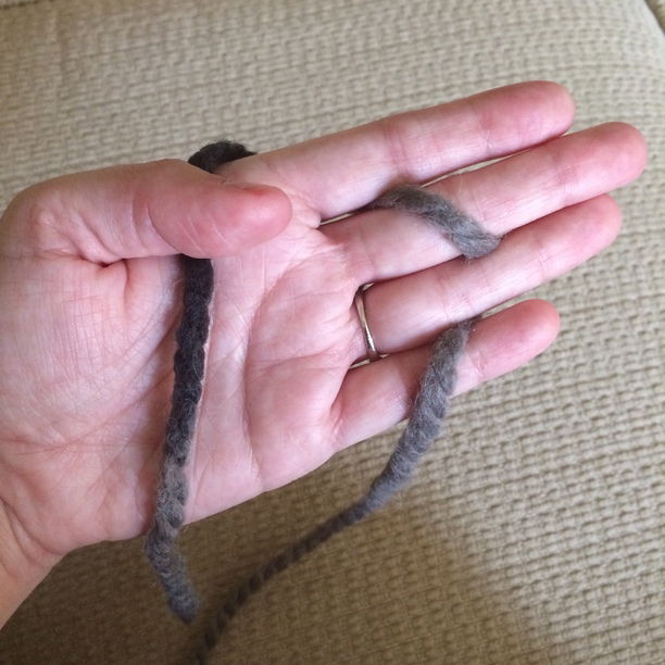 Photo of Elyse's palm with yarn across her palm and wound through her fingers