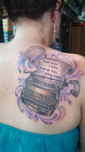 A typewriter tattoo on a woman's back with the quote "These words I write keep me from going insane."