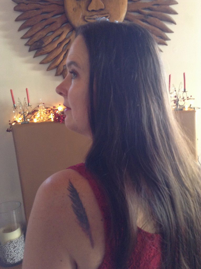 Tattoo of a feathered quill on a woman's shoulder blade