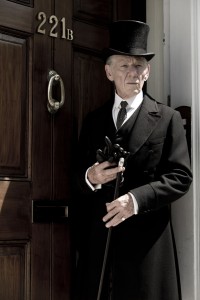 Ian McKellan standing in front of 221B in a top hat and black suit. He looks distinguished but a little confused