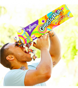 Dude with big biceps in a tight grey t-shirt pouring a box of Gobstoppers into his mouth - really weird commercial imagery on Amazon for this one