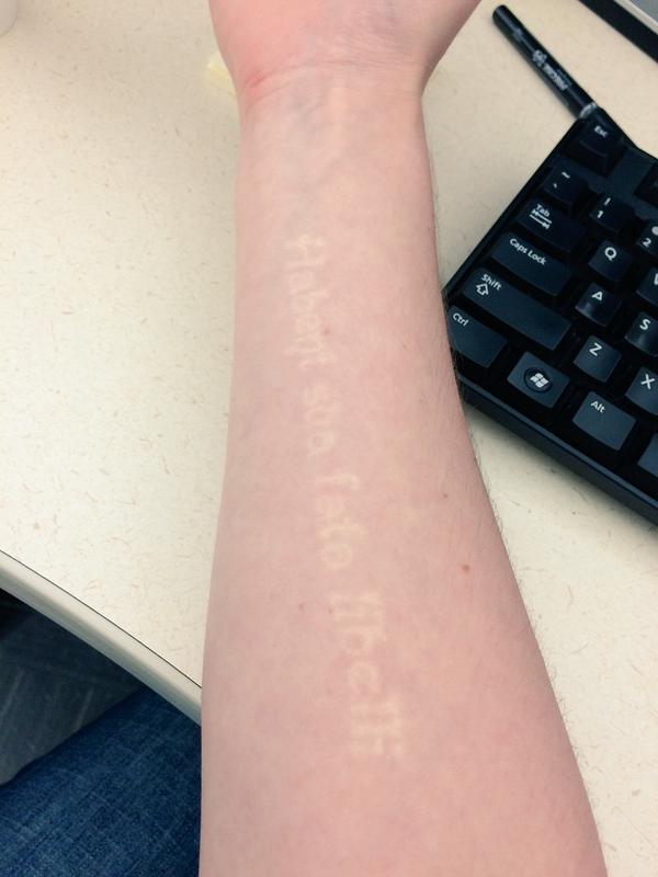 a white ink text tattoo running up her forearm 