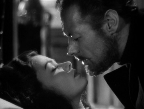 Rex Harrison very close to a sleeping Gene Tierney, about 2 inches from kissing her