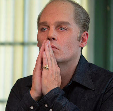 Depp as Bulger with his hands in a prayer position over his mouth. His contacts are indeed creepy