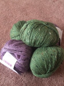Three skeins of a green wool yarn and one purple