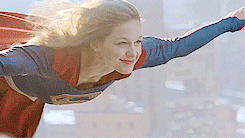 Supergirl flying gif - big smile as she flies over the city