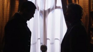 Prospero bringing Moriarty to life in silhouette against a backdrop of white curtains and black window framing