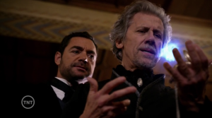 Moriarty looking over Propero's shoulder, looking tense and unhappy