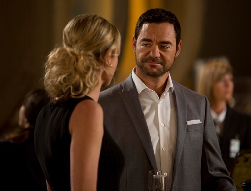 David S Lee as Moriarty, smiling at Col Baird, played by Rebecca Romijn