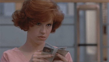 Molly Ringwald looking through a small book and sneering