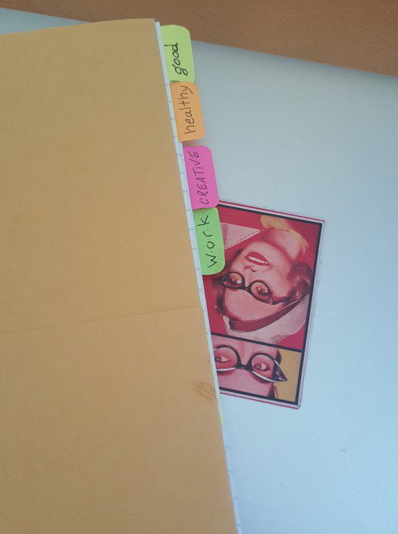 Close up of paper tabs labeled Good Healthy Creative Work on top of my laptop which has a sticker of The Ladies