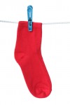 One red sock hanging on the clothesline. Image isolated on white background