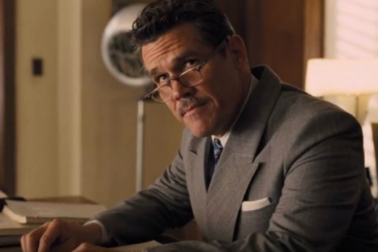 Eddie Mannix, played by Josh Brolin, wearing a dark grey suit looking over the tops of his glasses at someone.