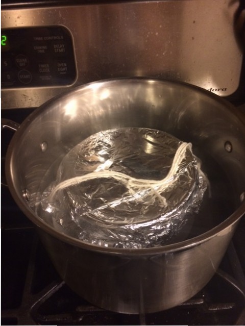 In the boiling water. There's a saucer underneath the basin to a) keep the basin from being directly on the hot pan, and b) to rattle a little so you don't forget you have a pudding on the stove
