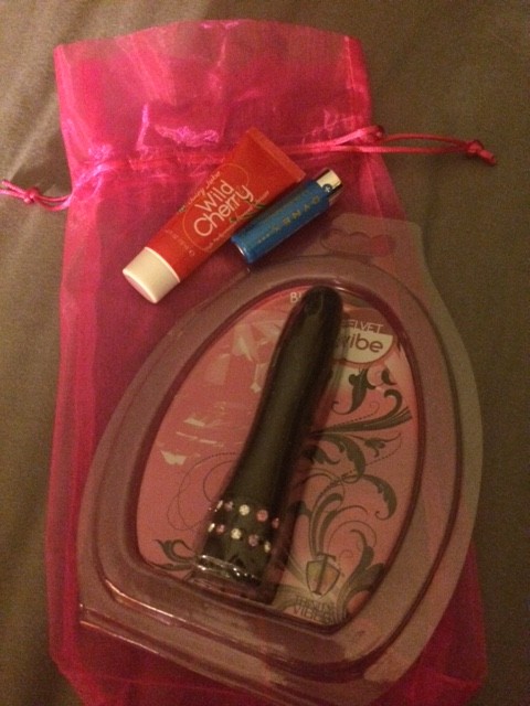 Tiny vibe in the plastic display, plus a battery and a tiny tube of lube in a pink organza drawstring bag