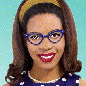 New Lady a Black woman with navy glasses, a navy polka dotted dress and pearls and a green headband. she's beautiful