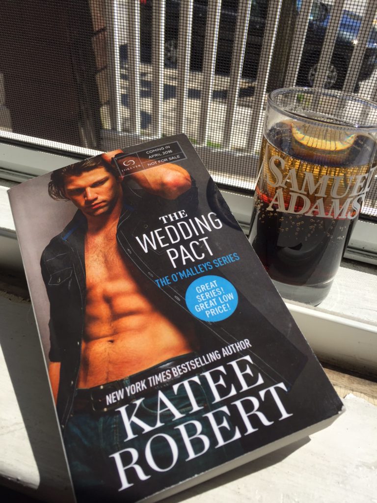 The Wedding Pact by Katee Robert next to a Black Velvet drink in a Sam Adams glass