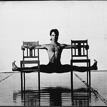 Paul Mercurio doing the splits on some chairs while shirtless. Of course.