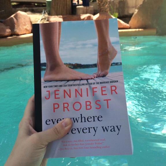 Close up of Elyse's hand holding a copy of Jennifer Probst's Everywhere and Every Way with the pool water as a backdrop