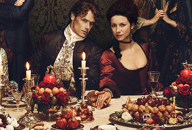 Claire and Jamie at a table hand in hand while peopel scheme around them - one of the promotional images that's gotten a lot of circulation because it's amazing