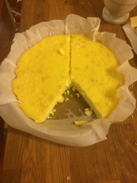 Cheese cake cut with wedge missing. Firm and yellow inside a parchment paper
