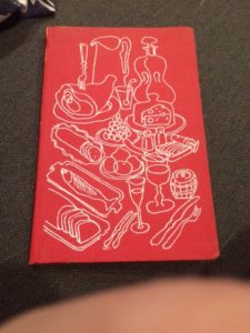 Old cookbook with redcover and line drawings of lots of food like bread, sliced meat, fish and a big ham. huge 