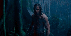 Tarzan in dim light flexing his arms 