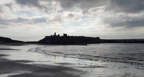 Evening shot of Peel Castle against the sky so the photograph looks black and white with the outline of the tower and the old cathedral jutting up from the island