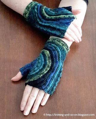 Blue swirl fingerless gloves with a starry-night kind of sky pattern with blue and green thick swirls crossing the back of the hand 