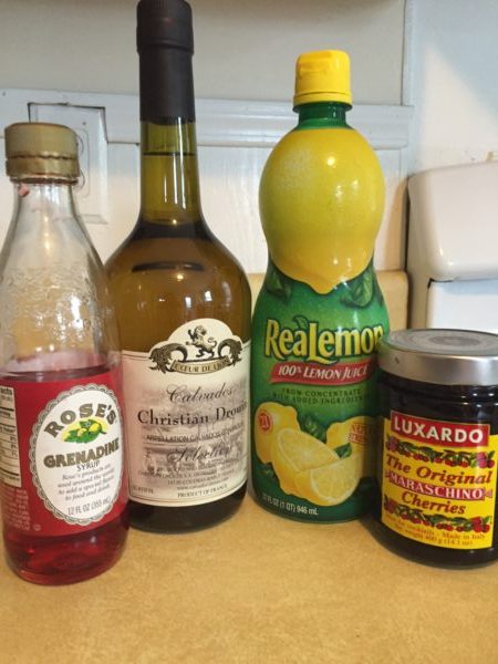 Ingredients for a Kingsbane cocktail: grenadine, lemon, maraschino cherries and calvados