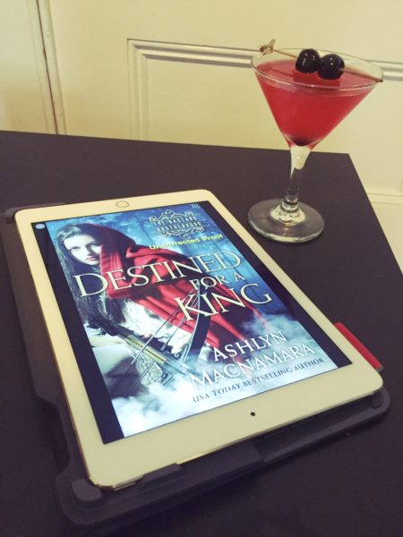 A pink Kingsbane cocktail next to a digital copy of Destined for a King