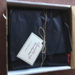 The open Bawdy Bookworms Box with black tissue paper and the fall theme tag