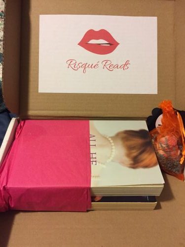 The Risque Reads box with two books wrapped in pink tissue paper and a decorative soap in the shape of a cupcake.