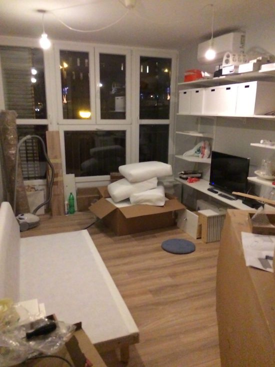Partially assembled Ikea couch in a condo with a ton of windows, with white walls and shelving