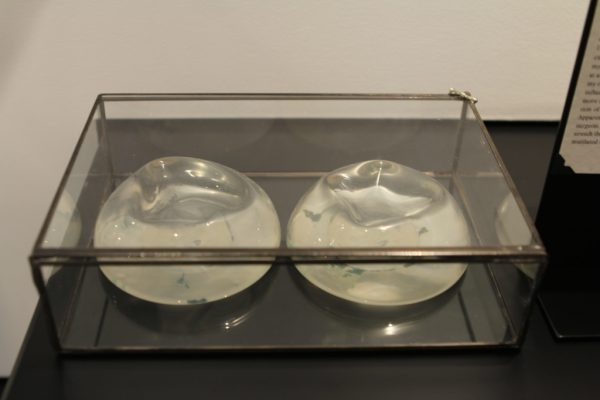A pair of breast implants are displayed in a glass box.