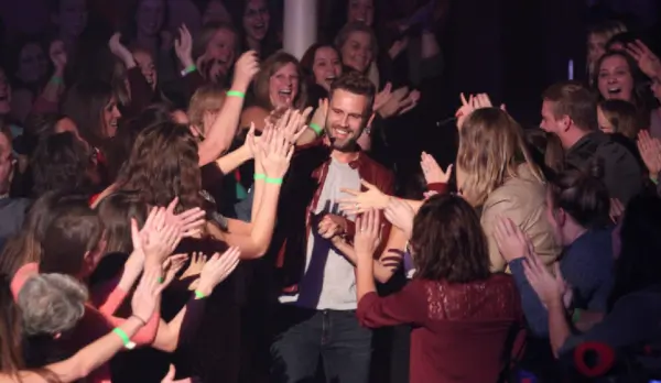 Nick and Danielle L walk down the aisle of the concert hall while fans cheer for them.