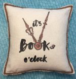 An oatmeal off white pillow that says It is book oclock