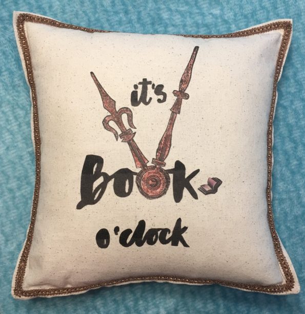 An oatmeal off white pillow that says It is book oclock