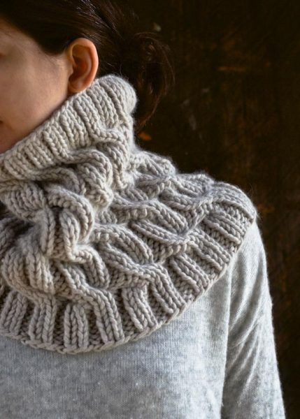 A woman wears a gorgous cabled cowl . 